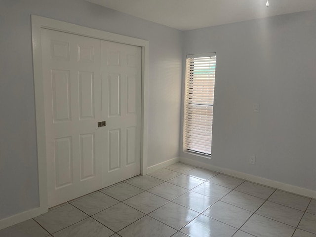 unfurnished bedroom with light tile patterned floors and a closet