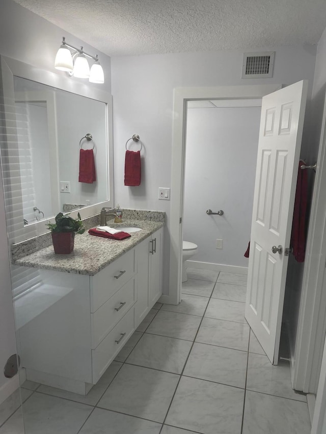 bathroom featuring vanity, toilet, and a textured ceiling