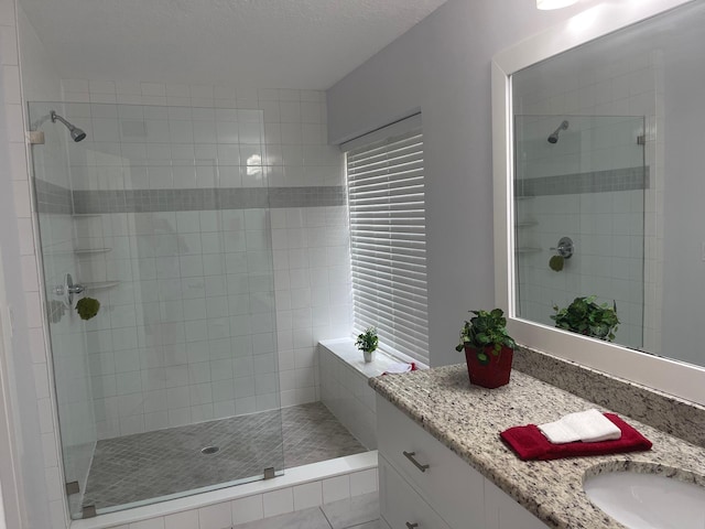 bathroom featuring vanity, a shower with door, and a textured ceiling