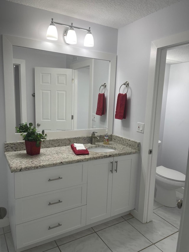 bathroom with vanity, a textured ceiling, and toilet