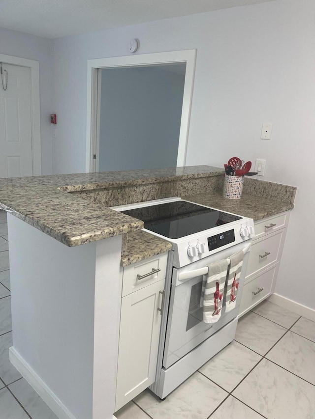 kitchen featuring light tile patterned floors, white cabinetry, dark stone counters, and range