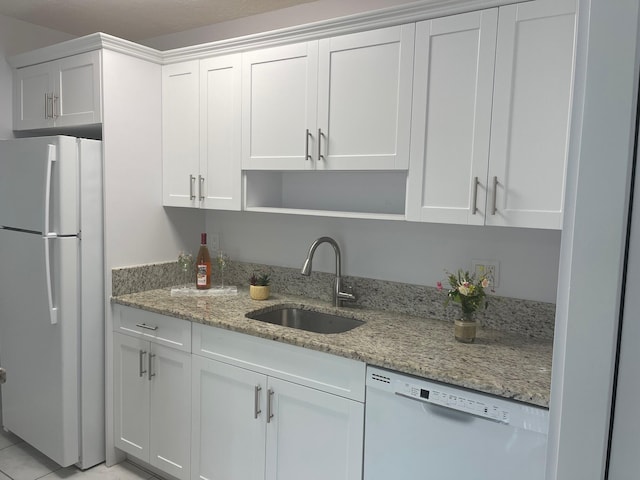 kitchen with white cabinetry, light stone counters, white appliances, and sink