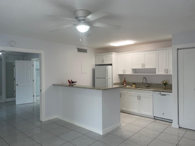 kitchen with kitchen peninsula, white appliances, sink, stone countertops, and white cabinetry