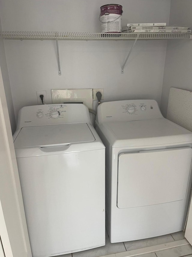 clothes washing area featuring light tile patterned floors and washer and clothes dryer