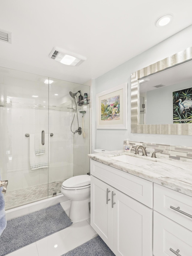 bathroom featuring tile patterned flooring, toilet, decorative backsplash, a shower with door, and vanity