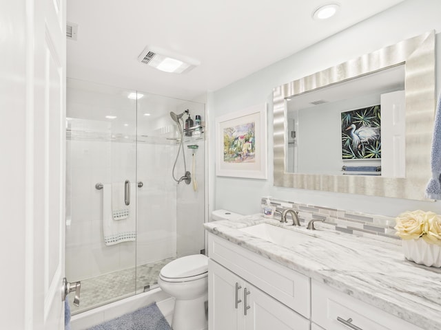 bathroom with vanity, toilet, and a shower with door