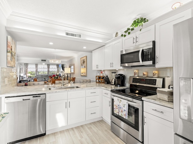 kitchen featuring kitchen peninsula, appliances with stainless steel finishes, decorative backsplash, sink, and white cabinetry