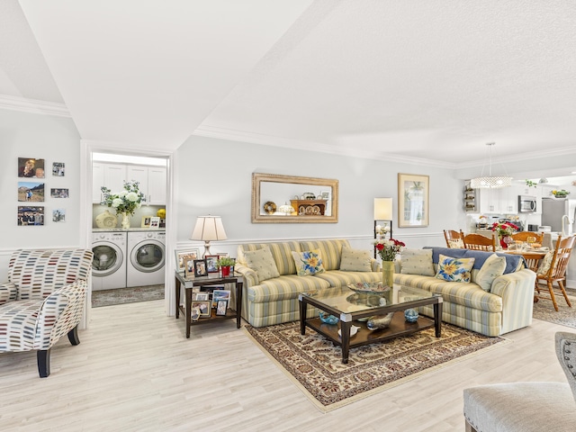 living room with a textured ceiling, light hardwood / wood-style flooring, washer and clothes dryer, and ornamental molding