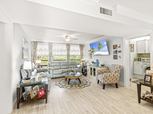 living room featuring light wood-type flooring, washer / clothes dryer, ceiling fan, and ornamental molding