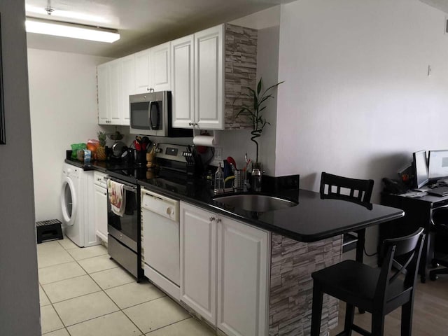 kitchen with white cabinetry, sink, a kitchen breakfast bar, kitchen peninsula, and appliances with stainless steel finishes