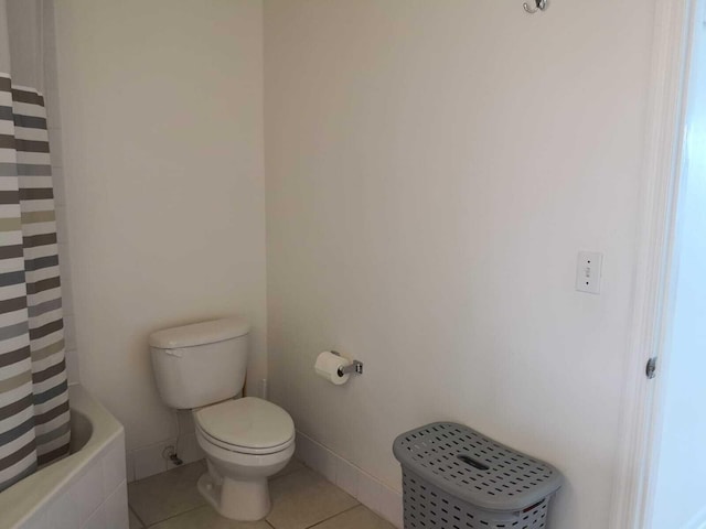 bathroom with tile patterned flooring, shower / bath combination with curtain, and toilet