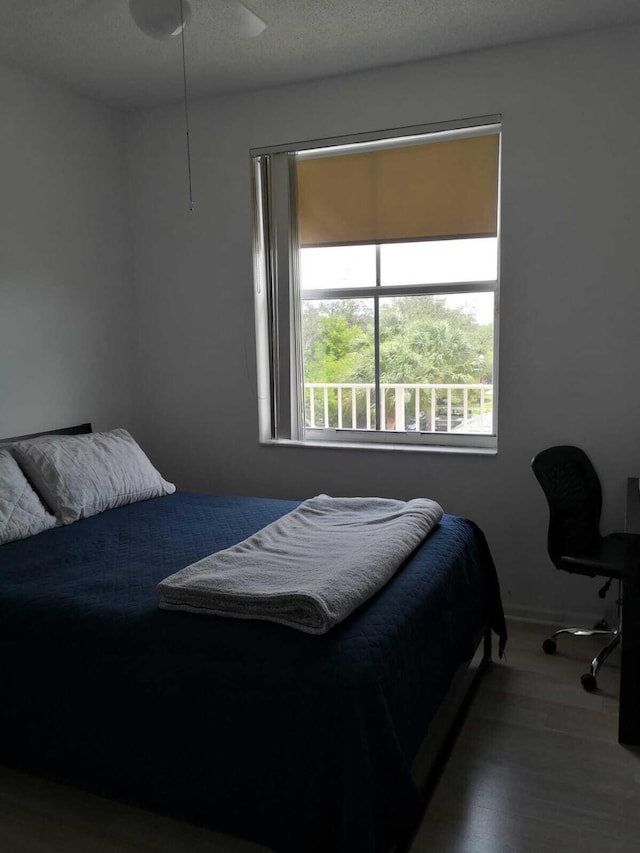 bedroom with a textured ceiling, hardwood / wood-style flooring, and ceiling fan