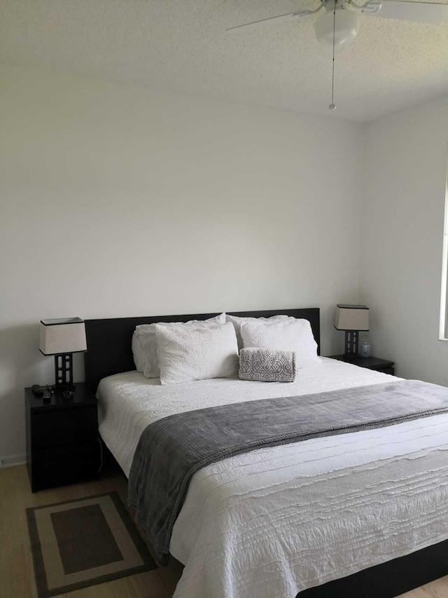 bedroom featuring ceiling fan, wood-type flooring, and a textured ceiling