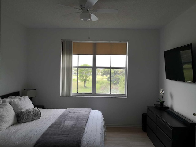 bedroom featuring ceiling fan, light wood-type flooring, and a textured ceiling