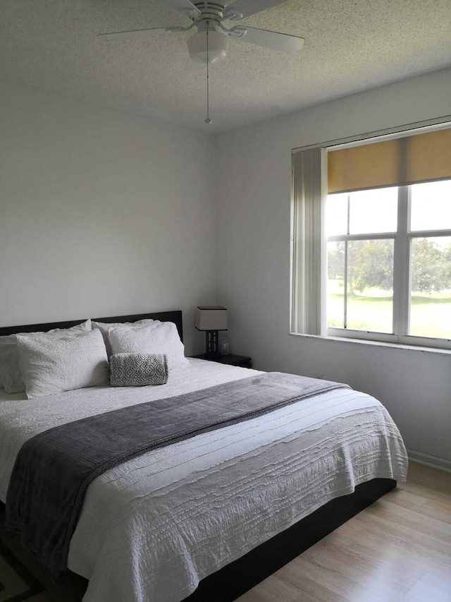 bedroom with a textured ceiling, light hardwood / wood-style flooring, and ceiling fan