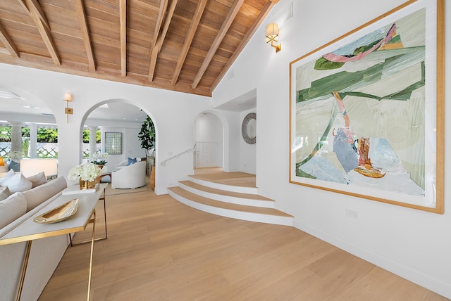 corridor featuring beam ceiling, light wood-type flooring, high vaulted ceiling, and wood ceiling