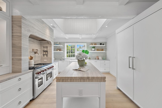 kitchen with white cabinets, a kitchen island, double oven range, and light hardwood / wood-style floors