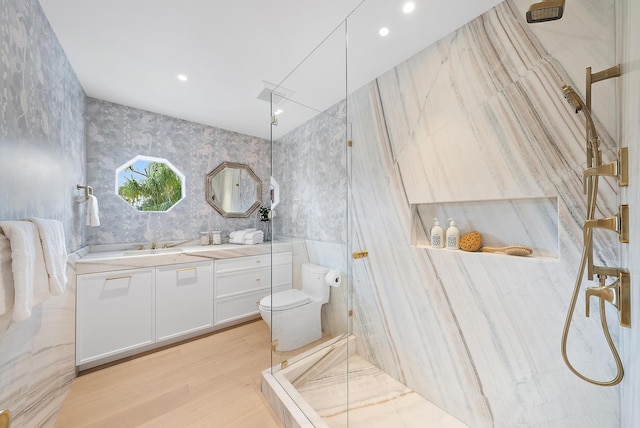 bathroom with hardwood / wood-style floors, vanity, toilet, and tiled shower