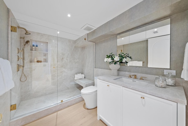 bathroom with hardwood / wood-style floors, vanity, toilet, and walk in shower