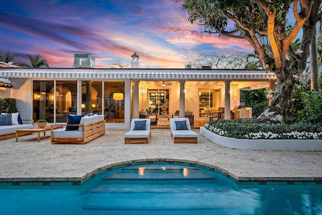 back house at dusk featuring ceiling fan, a patio area, and an outdoor living space