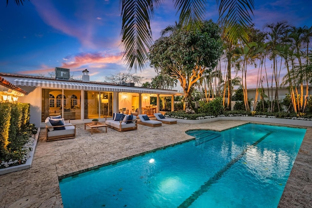 pool at dusk with an outdoor hangout area, a patio, and central AC