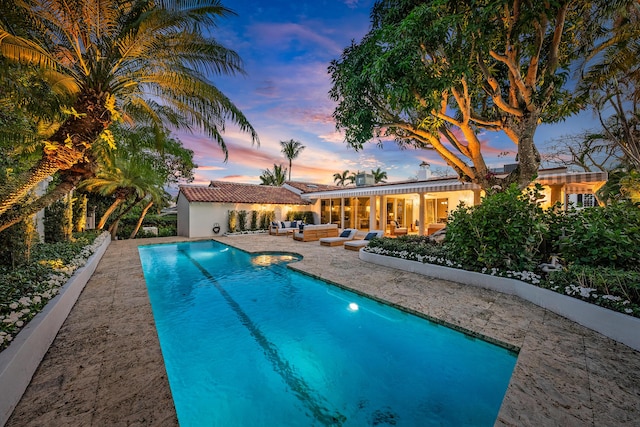 pool at dusk featuring an outdoor hangout area and a patio area