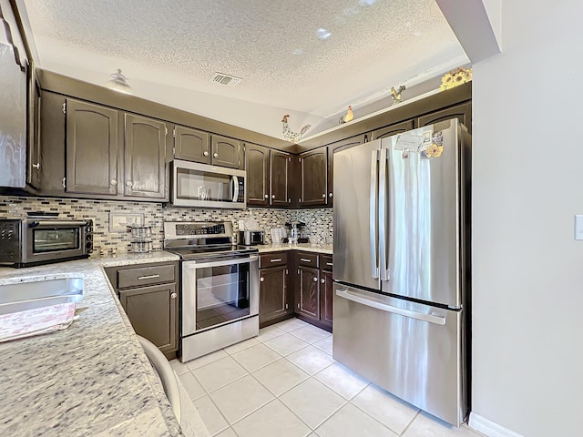 kitchen with dark brown cabinets, stainless steel appliances, and a textured ceiling