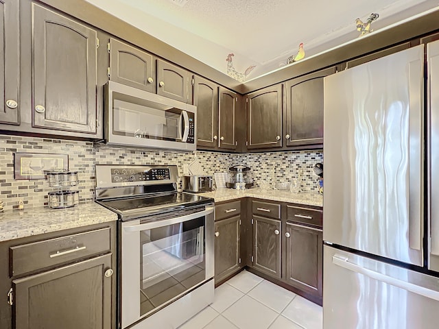 kitchen with light tile patterned floors, dark brown cabinetry, stainless steel appliances, and tasteful backsplash