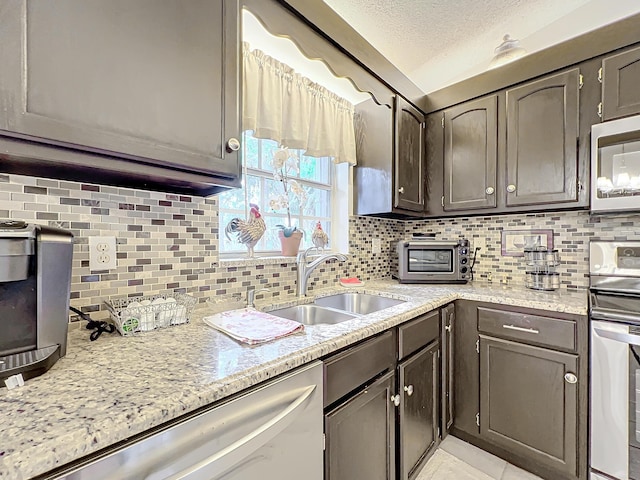 kitchen featuring decorative backsplash, sink, a textured ceiling, and appliances with stainless steel finishes