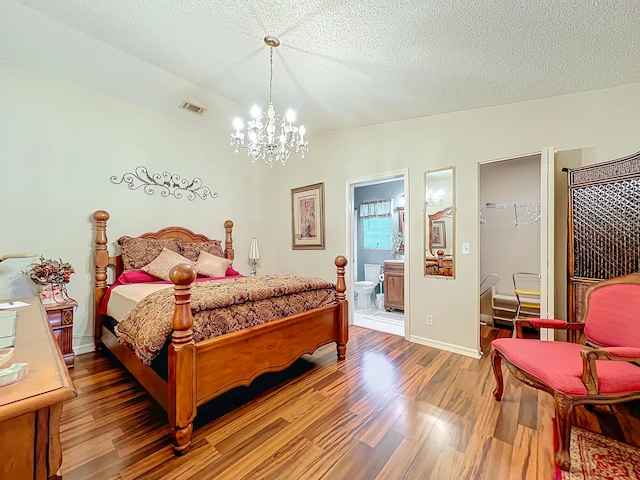 bedroom with ensuite bath, an inviting chandelier, a textured ceiling, a closet, and hardwood / wood-style flooring