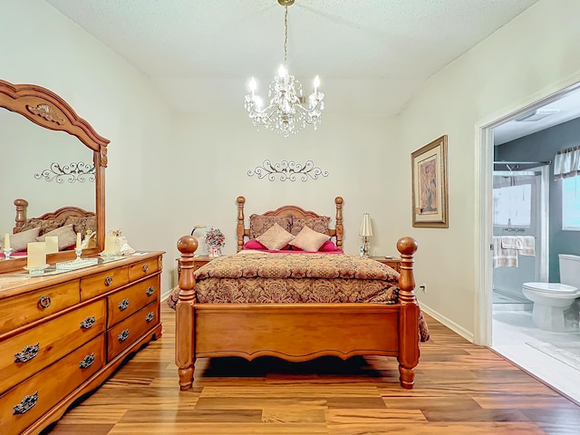 bedroom featuring connected bathroom, a notable chandelier, and light wood-type flooring