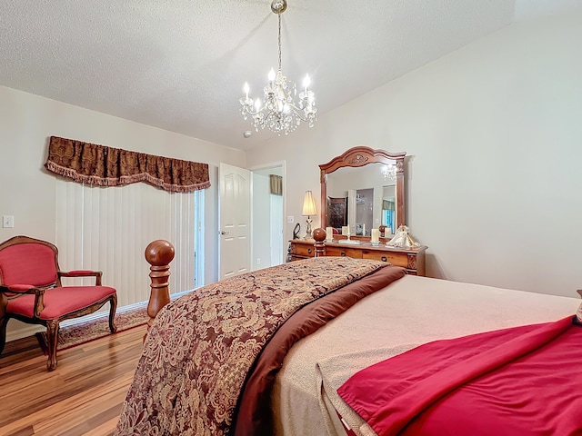 bedroom with light hardwood / wood-style floors, a textured ceiling, and an inviting chandelier