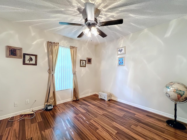 unfurnished room with ceiling fan, dark wood-type flooring, and a textured ceiling