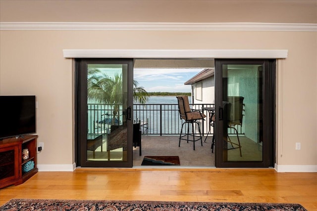 entryway featuring wood-type flooring, a water view, and ornamental molding