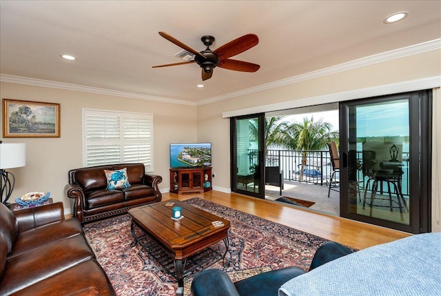 living room with hardwood / wood-style flooring, ceiling fan, and crown molding