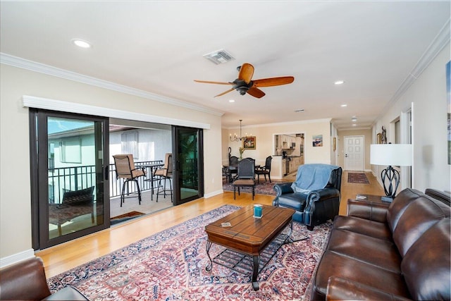 living room with hardwood / wood-style floors, ceiling fan with notable chandelier, and crown molding