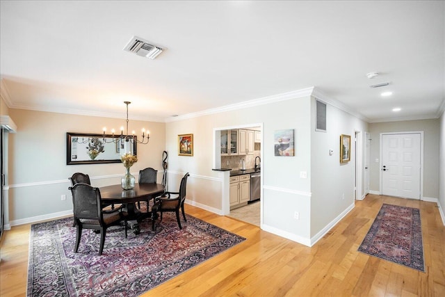 dining room with crown molding, a notable chandelier, and light wood-type flooring