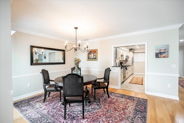 dining space featuring light wood-type flooring, ornamental molding, and a chandelier