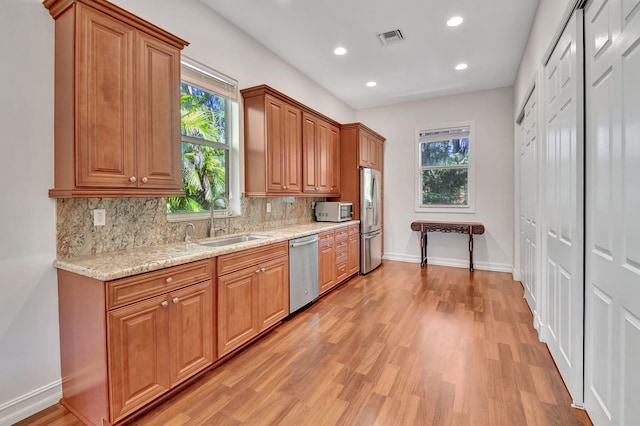 kitchen featuring light stone counters, sink, plenty of natural light, and stainless steel appliances