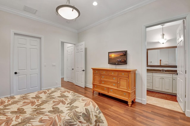 bedroom with light wood-type flooring, ensuite bathroom, ornamental molding, and sink