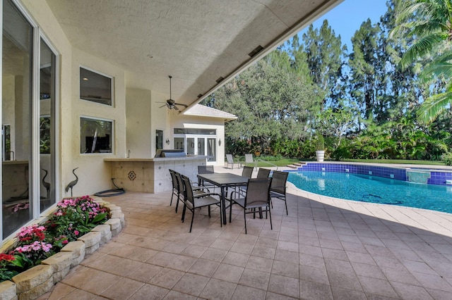 view of pool featuring exterior bar, ceiling fan, a patio area, and exterior kitchen