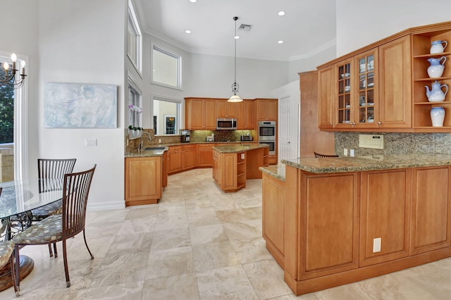 kitchen featuring stainless steel appliances, light stone counters, backsplash, kitchen peninsula, and pendant lighting