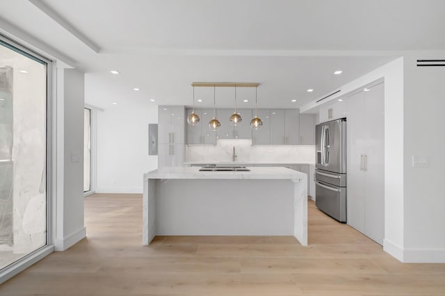 kitchen with a center island, tasteful backsplash, stainless steel fridge with ice dispenser, pendant lighting, and light wood-type flooring