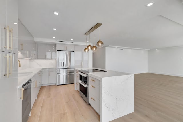 kitchen with white cabinetry, sink, hanging light fixtures, stainless steel appliances, and a kitchen island