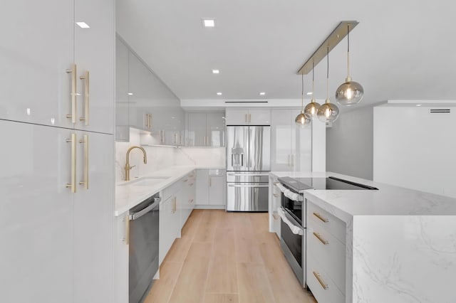 kitchen featuring appliances with stainless steel finishes, white cabinetry, hanging light fixtures, and sink