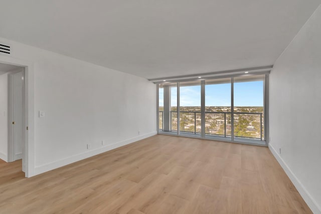 spare room featuring light hardwood / wood-style floors and expansive windows