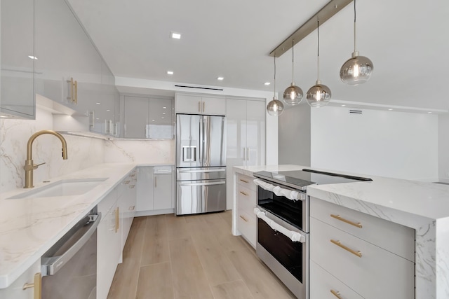 kitchen featuring decorative backsplash, appliances with stainless steel finishes, sink, white cabinets, and hanging light fixtures