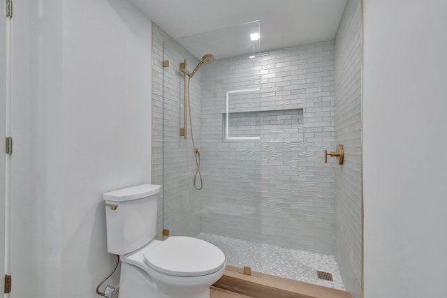 bathroom with a tile shower, hardwood / wood-style flooring, and toilet