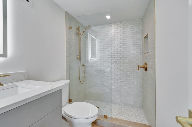 bathroom featuring tiled shower, vanity, and toilet