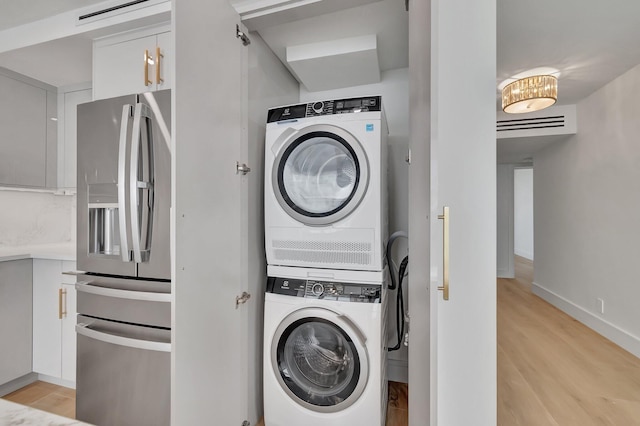 washroom featuring light wood-type flooring and stacked washing maching and dryer